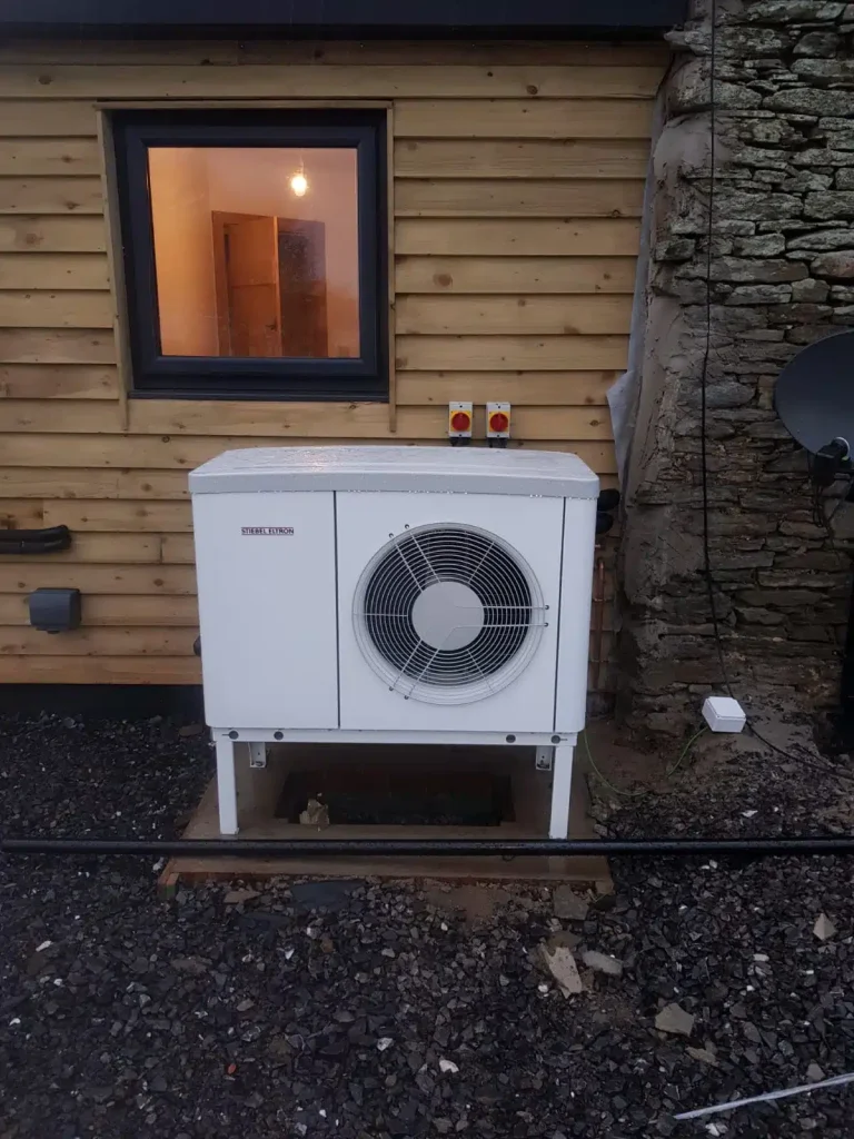 Air source heat pump outdoor unit against timber cladding